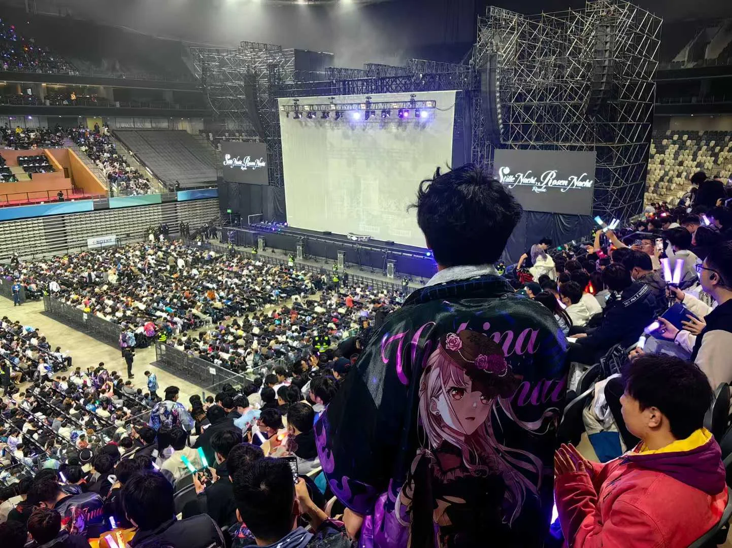 从看台俯瞰演出场馆，前方观众穿着湊友希那主题外套