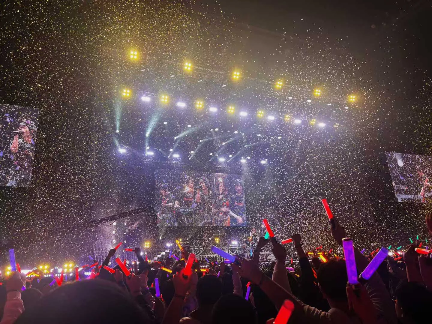 演出终场时金色彩带雨落向舞台与挥舞手灯的观众